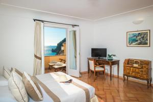 a hotel room with a bed and a desk and a window at Hotel L'Ancora in Positano