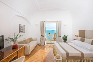 a bedroom with a bed and a couch and a window at Hotel L'Ancora in Positano +62 photos