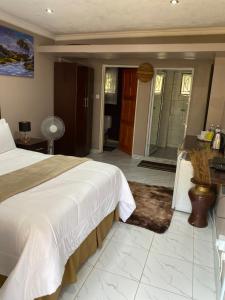 a bedroom with a large bed and a bathroom at Green Whisper BnB in Umtali
