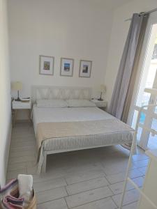a white bedroom with a bed and a window at camera con terrazza vicino al mare e pineta in Follonica