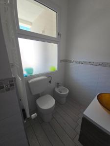 a bathroom with a toilet and a window and a sink at camera con terrazza vicino al mare e pineta in Follonica +19 photos