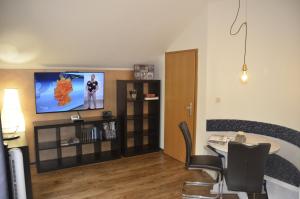 a living room with a table and a tv on the wall at Ferienwohnung Wildgatter in Grafenwiesen