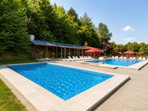 a large swimming pool with chairs and a building at Deny Inn Harmony in Zărneşti