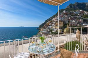 a table on a balcony with a view of the ocean at Hotel L'Ancora in Positano