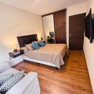 a bedroom with a bed with blue pillows and a couch at Depar 1 Dormitorio B in Cochabamba