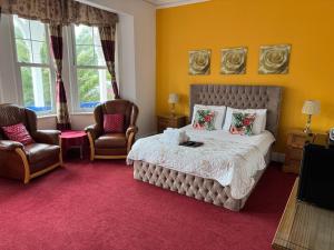 a bedroom with a large bed and two chairs at Hotel Hudson in Torquay