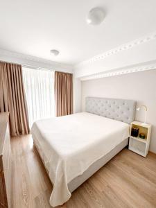 a white bedroom with a large bed and a window at WRW Airport Residence in Otopeni +17 photos