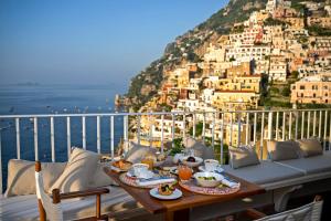 a table with food on a balcony with a view of the city at Hotel L'Ancora in Positano