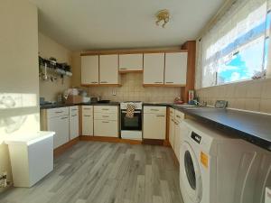 a kitchen with white cabinets and a washer and dryer at E Gardens Apartment in Nottingham