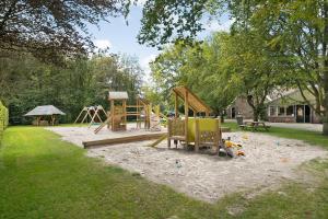 a park with a playground with a slide and a swing set at Boslodge 7 personen in Tiendeveen