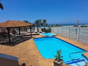 a blue swimming pool with a gazebo and the ocean at #9 Illovo Views in Kingsborough