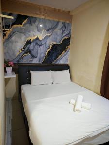 a white bed with a cross on top of it at 28 Gred Hotel in Bukit Mertajam