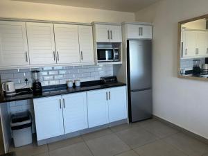 a kitchen with white cabinets and a stainless steel refrigerator at #9 Illovo Views in Kingsborough