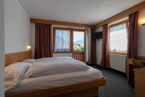 a bedroom with two beds and a large window at Bormiohomes - Case SteLu in Bormio