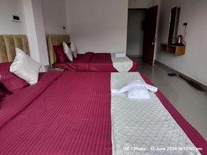 two beds in a room with red and white sheets at The Great Hill View Hotel in Phata