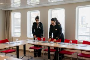 two women standing at a table in a room with red chairs at ss Rotterdam by WestCord in Rotterdam