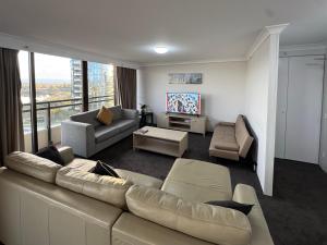 a living room with a large couch and a tv at Lakefront Panorama – Classic in Canberra