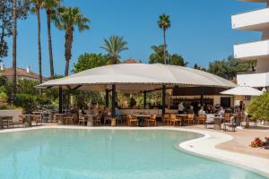 a pool at a resort with people sitting at tables and an umbrella at Senator Banus Adults Only Recommended in Estepona