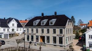 ein großes weißes Haus mit schwarzem Dach in der Unterkunft Bakerigården in Lillesand