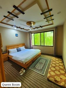 a bedroom with a large bed and a large window at HIKK Inn Skardu in Skardu