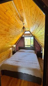 a bed in a room with a wooden ceiling at Alamabari Inn in Kobuleti