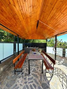 a patio with a table and benches and a wooden ceiling at Alamabari Inn in Kobuleti +14 photos
