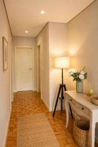 a hallway with a white door and a table with a lamp at Casa do Alto Vila Caiz in Amarante +15 photos