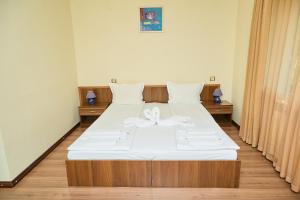 ein Schlafzimmer mit einem Bett mit weißen Laken und einer Schleife in der Unterkunft Family Hotel Fedora in Ribarica