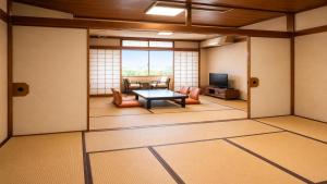ein Wohnzimmer mit einem Tisch und einem Fernseher in der Unterkunft Livemax Resort Isawa Onsen in Fuefuki