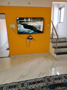 a living room with a tv on a yellow wall at Umahomestay in Nashik