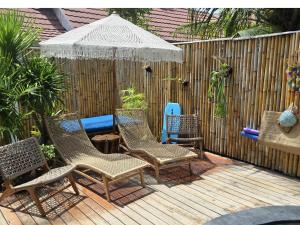 a group of chairs and an umbrella on a deck at Villa Asmara Gili Air in Gili Islands