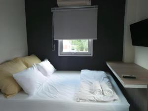 a bed with white sheets and pillows and a window at JamPark City in Bangkok