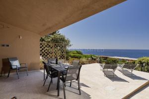 a patio with a table and chairs and the ocean at Villetta Luce Marina in Costa Paradiso
