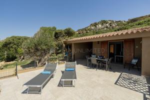 a house with a patio with a table and chairs at Villetta Luce Marina in Costa Paradiso