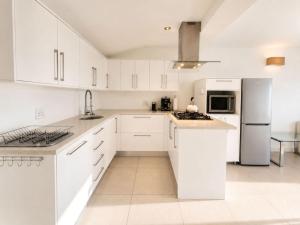 a white kitchen with white cabinets and appliances at '24 Gordonia', Spacious Condo - Sleeps 7, Sea Front, Easy Beach access in Gordonʼs Bay