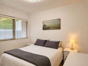 a white bedroom with a bed and a window at '24 Gordonia', Spacious Condo - Sleeps 7, Sea Front, Easy Beach access in Gordonʼs Bay