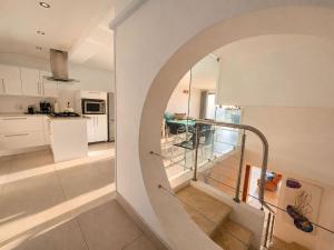 an arched hallway leading to a kitchen with white cabinets at '24 Gordonia', Spacious Condo - Sleeps 7, Sea Front, Easy Beach access in Gordonʼs Bay +33 photos