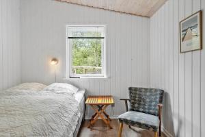 a bedroom with a bed and a chair and a window at LF10316-Hurup-Thy-Vagtelvej-16 in Sønder Ydby