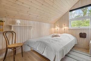 a bedroom with a bed and a chair and a window at 8923-Allingabro-Poppelvej-17 in Allingåbro