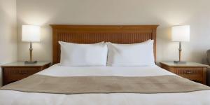 ein Schlafzimmer mit einem Bett mit weißen Kissen und zwei Lampen in der Unterkunft Coast Capri Hotel in Kelowna + 97 Fotos