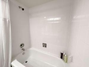 ein weißes Badezimmer mit Badewanne und Dusche in der Unterkunft Coast Capri Hotel in Kelowna
