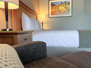 ein Hotelzimmer mit einem Bett und einem Stuhl in der Unterkunft Coast Capri Hotel in Kelowna