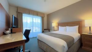 ein Hotelzimmer mit Bett, Schreibtisch und Fenster in der Unterkunft Coast Capri Hotel in Kelowna