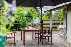 a wooden table and chairs with an umbrella on a deck at 588-N-Hundested-Krusemyntestien-5 in Hundested