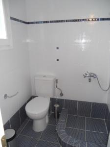 a bathroom with a toilet and a tiled floor at Afales Villa and Studios in Exoyí