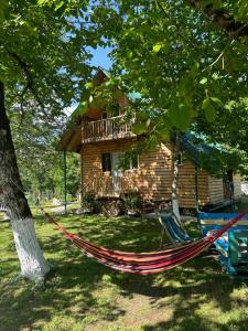 a hammock in front of a log cabin at DEDULETI დედულეთი in Ambrolauri