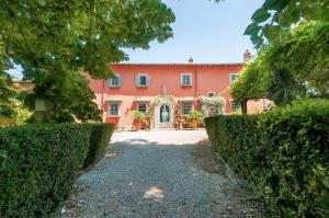 an exterior view of a pink house with bushes at Villa Il Rossignolo con Piscina in Grassina