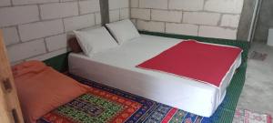 a bed with white sheets and a red blanket at Komachi House in Limbung +82 photos