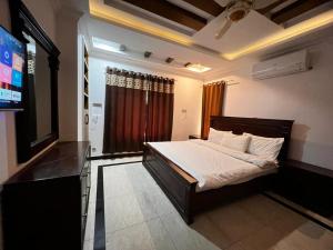 a bedroom with a bed and a flat screen tv at Mountain Villa Family Guest House in Islamabad