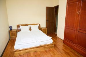 a bedroom with a bed with white sheets and wooden floors at Guest House Fedor in Ribarica